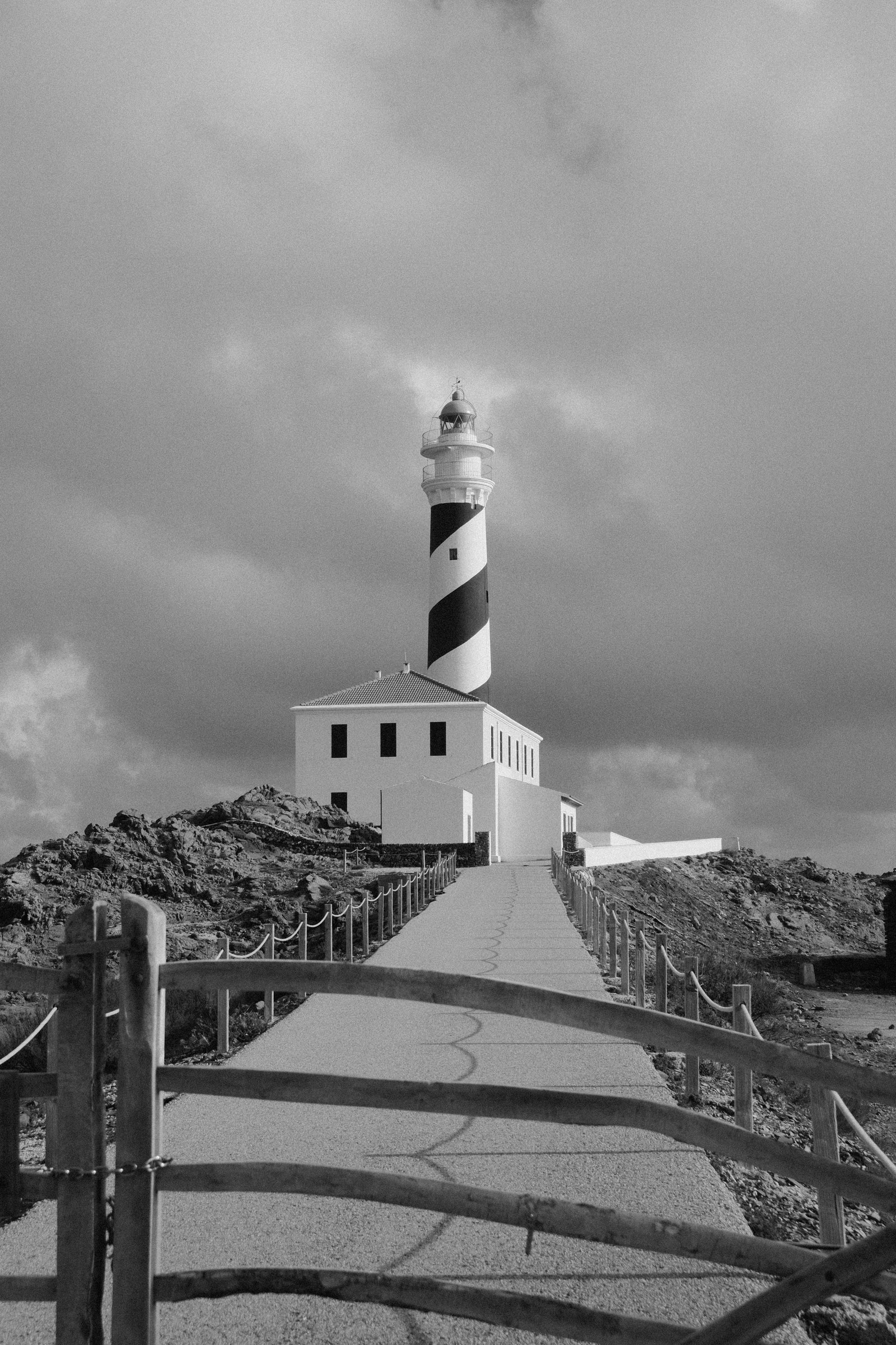 Torre de franjas negras del faro de Favàritx sobre el edificio blanco junto al camino